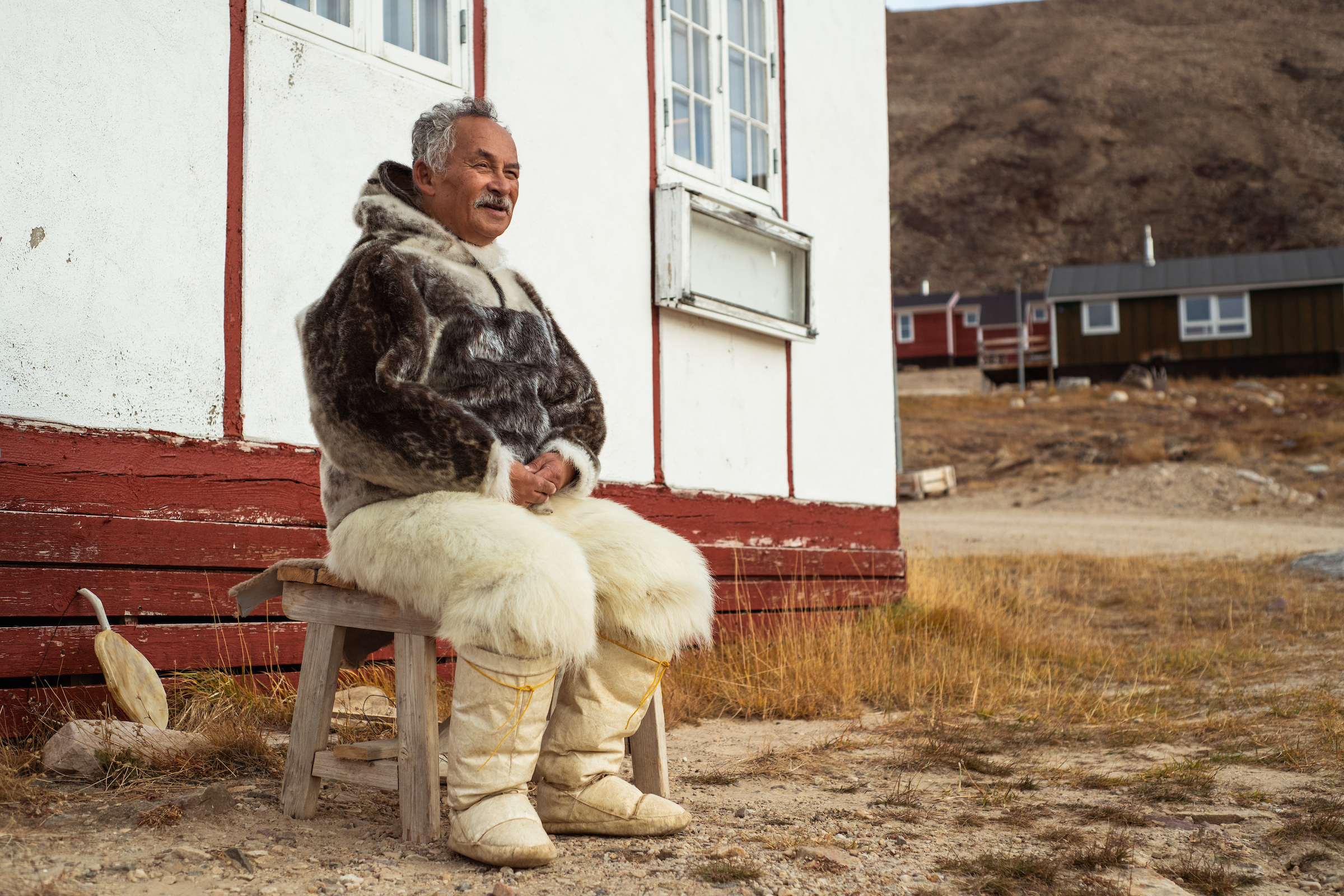 Man sitter utanför museet Qaanaaq på Grönland.